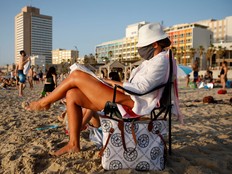 A woman wears a face mask as she sits by the Mediterranean Sea in Tel Aviv as COVID-19 restrictions were eased in Israel, May 21, 2020.
