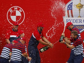 Team USA's Dustin Johnson sprays champagne on his teammates as they celebrate after winning the Ryder Cup against Team Europe.