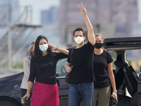 Michael Kovrig, centre right, waves to media as his wife Vina Nadjibulla, centre left, and sister Ariana Botha after his arrival at Pearson International Airport in Toronto, Saturday, Sept. 25, 2021. Two Canadians who were imprisoned in China for nearly three years are home. THE CANADIAN PRESS/Frank Gunn