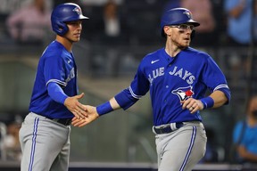 Blue Jays baserunners Jake Lamb, left, and Danny Jansen, right, slap hands after scoring on a single by Marcus Semien during the fourth inning of a game against the New York Yankees at Yankee Stadium in New York City, Wednesday, Sept. 8, 2021.