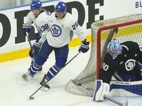 Maple Leafs defender Rasmus Sandin (38) chases down forward Ondrej Kase (25) in front of goalie Joseph Woll on the first day of on ice activity at training camp on Thursday.