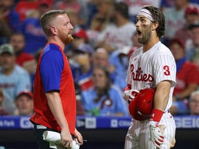 Phillies' Bryce Harper tries to get something out of his eye as a member of the medical staff assists during the fifth inning of a game against the Diamondbacks at Citizens Bank Park in Philadelphia, Aug. 27, 2021.