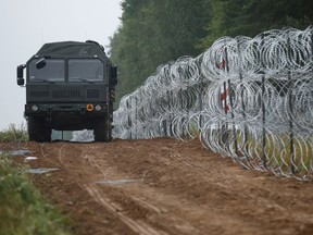 A vehicle patrols next to a fence built by Polish soldiers on the border between Poland and Belarus near the village of Nomiki, Poland August 26, 2021.