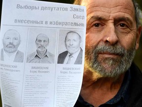 Boris Vishnevsky poses with a printed image of a mockup of an official election poster featuring nearly identical photos of him and two other Boris Vishnevskys side by side in Saint Petersburg on September 6, 2021.