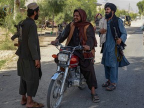 A Taliban fighter (left) mans a checkpoint in Kandahar on September 21, 2021.