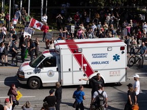 An ambulance passes through a crowd of people protesting COVID-19 vaccine passports and mandatory vaccinations for healthcare workers, in Vancouver, on Wednesday, Sept. 1, 2021. The protest began outside Vancouver General Hospital and police estimated the crowd gathered to be as many as 5,000 people.