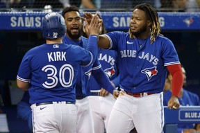 Alejandro Kirk of the Blue Jays is welcomed to the dugout by Vladimir Guerrero Jr. as he scores in the fourth inning. COLE BURSTON/GETTY IMAGES