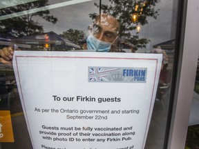 Host Jason Singh with a notice of Ontario's new vaccination requirement at Firkin on the Bay pub in the Humber Bay Shores neighbourhood in Toronto on Tuesday September 21, 2021.