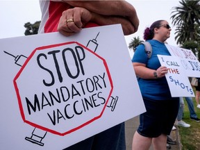 Anti-vaccination protesters holding signs take part in a rally against Covid-19 vaccine mandates.