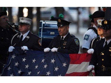 New York police and firefighters hold a U.S. flag as a band plays the U.S. national anthem at the National 9/11 Memorial during a ceremony commemorating  the 20th anniversary of the 9/11 attacks on the World Trade Center, in New York, on Sept. 11, 2021.