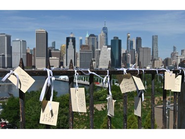 Notes are posted on a fence in Brooklyn across the East River from Manhattan marking the 20th anniversary of the 9/11 attacks on the World Trade Center, in New York, on Sept. 11, 2021.