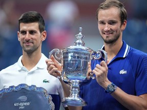 Novak Djokovic of Serbia and Daniil Medvedev of Russia celebrate with the finalist and championship trophies, respectively, after their match in the men's singles final on day fourteen of the 2021 U.S. Open tennis tournament at USTA Billie Jean King National Tennis Center.
