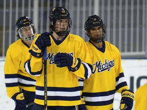 From left. University of Michigan's Kent Johnson, Owen Power and Matty Beniers watch during practice.