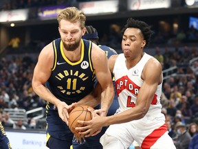 Domantas Sabonis #11 of the Indiana Pacers and Scottie Barnes #4 of the Toronto Raptors battle for a loose ball during the game at Gainbridge Fieldhouse on October 30, 2021 in Indianapolis, Indiana.
