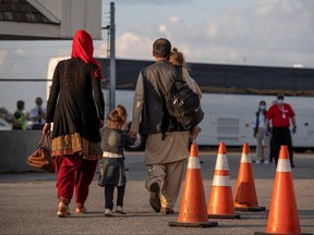 Afghan refugees who supported Canada's mission in Afghanistan prepare to board buses after arriving in Canada at Toronto Pearson International Airport, Aug. 24, 2021.