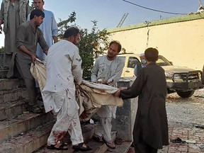 Afghan men carry the body of a victim to an ambulance after a bomb attack at a mosque in Kunduz on October 8, 2021.