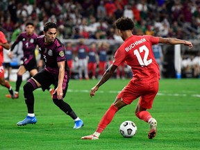 Canada's forward Tajon Buchanan, right, challenges Mexico defender Carlos Salcedo during the Concacaf Gold Cup football match semifinal between Mexico and Canada at NRG stadium in Houston, Texas on July 29, 2021.