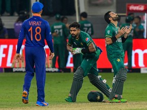 Pakistan's team captain Babar Azam (C) and his teammate Mohammad Rizwan (L) react following their victory as India's captain Virat Kohli looks on during the ICC mens Twenty20 World Cup cricket match between India and Pakistan at the Dubai International Cricket Stadium in Dubai on October 24, 2021.