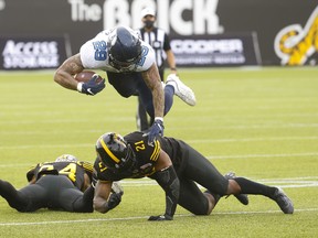 Argonauts wide receiver Kurleigh Gittens Jr., leaps over linebacker Simoni Lawrence (21) and defensive back Desmond Lawrence during the Double Blue’s 24-23 comeback win in Hamilton last Monday.