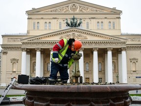A municipal worker checks and cleans a fountain in front of The Bolshoi Theatre as part of closing the summer fountain season in downtown Moscow on Oct. 1, 2021.