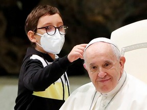 A boy approaches Pope Francis during the weekly general audience at the Vatican, Oct. 20, 2021.