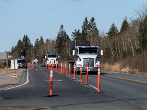 Transport trucks bypass a police checkpoint at the Manitoba-Ontario provincial boundary during the period where non-essential travel into the province of Ontario was limited due to the COVID pandemic on April 19, 2021.