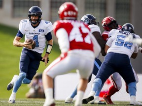 Toronto Argonauts quarterback McLeod Bethel-Thompson, left, looks for an opening as he runs the ball against the Calgary Stampeders during CFL football action in Calgary, Saturday, Aug. 7, 2021.