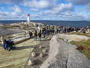 Onlookers attend the opening of a new viewing deck in Peggy's Cove, N.S. on Monday, Oct. 18, 2021. The 1,300 square metre deck provides accessible public space overlooking the iconic lighthouse.