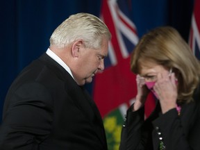 Ontario Premier Doug Ford trades places with Health Minister Christine Elliott during a press briefing in Toronto, Friday, Oct. 22, 2021.