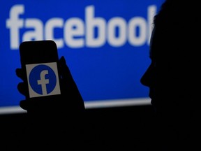 In this file photo illustration, a smart phone screen displays the logo of Facebook on a Facebook website background.