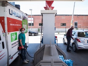 People pump gas into their vehicles at a Esso station  in Toronto on Tuesday, June 15, 2021.