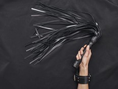 Explore each other's. Top view of female hands in black leather handcuffs holding a whip against of black silk.