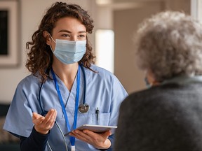 Young doctor visits senior woman with surgical mask