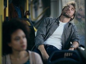 Exhausted mid adult man taking a nap while traveling by public transport.