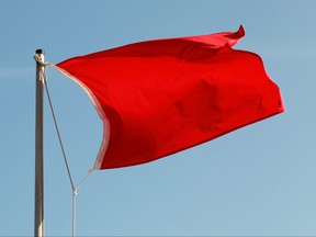 Red flag on a beach waving above blue sky
