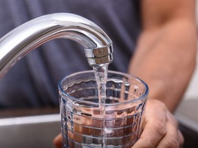 Hand with drinking glass filling water from kitchen faucet