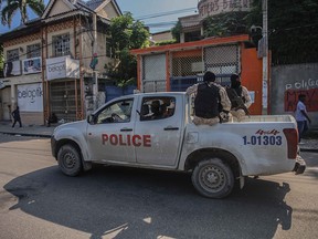 Armed police ride in the back of a truck after the streets of the Haitian capital Port-au-Prince were deserted following a call for a general strike launched by several professional associations and companies to denounce insecurity in Port-au-Prince on October 18, 2021.