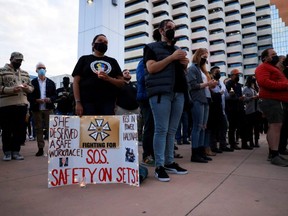 A woman displays a sign calling for workplace safety at a vigil for cinematographer Halyna Hutchins, who died after being shot by Alec Baldwin on the set of his movie "Rust," in Albuquerque, New Mexico, Saturday, Oct. 23, 2021.