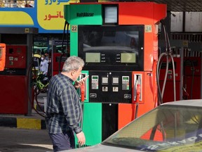 An Iranian man talks on a phone as he waits by his car to fill up at a service station in Tehran, Tuesday, Oct. 26, 2021, amid a nationwide disruption of the gasoline distribution system.