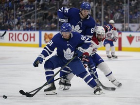 Maple Leafs' Mac Hollowell (81) tries to control the puck as forward Ilya Mikheyev blocks out Montreal Canadiens' Mathieu Perreault during the second period at Scotiabank Arena on Tuesday, Oct. 5, 2021.