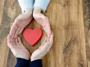 Heart surrounded by man and woman's hand