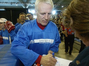 Former New York Islanders star Mike Bossy signs an Islanders poster for a fan.