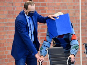 Defendant Josef S gets help from his lawyer Stefan Waterkamp (left) to hide his face behind a folder as he arrives for his trial in Brandenburg an der Havel, northeastern Germany, on October 7, 2021.
