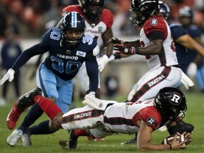 Ottawa Redblacks quarterback Caleb Evans drops the ball but recovers it as Toronto Argonauts linebacker Travis Feeney looks on in Toronto on Wednesday. The Canadian Press