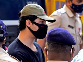 Bollywood actor Shah Rukh Khan's son Aryan Khan is being escorted by law enforcement officials outside the Narcotics Control Bureau (NCB) office after he was allegedly brought in for questioning along with others following a raid at a party on a cruise ship, in Mumbai on Oct. 3, 2021.