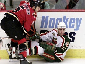 Calgary Flames defenceman Steve Montador (5) knocks down Minnesota Wild forward Pascal Dupuis (11) in Calgary, November 7, 2003.
