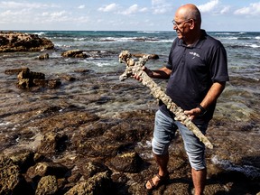 Yaakov Sharvit of the IAA holds a sword believed to have belonged to a Crusader who sailed to the Holy Land almost a millennium ago after it was recovered from the Mediterranean seabed by an amateur diver, the Israel Antiquities Authority said, Caesarea, Israel October 18, 2021.