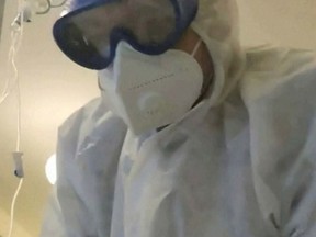 Local resident Sergei (whose last name was not given) disguised as a doctor in a protective suit takes care of his grandmother suffering from COVID-19 in a hospital ward in Tomsk, Russia October 28, 2021, in this screengrab taken from a video.