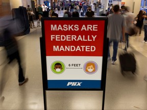 Air travellers make their way past a sign mandating face masks at Phoenix international airport in Phoenix, Ariz., Sept. 24, 2021.