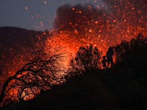 A woman climbs a hill with a child to see the Cumbre Vieja volcano as it continues to erupt in Tacande de Arriba on the Canary Island of La Palma, Spain, October 2, 2021.